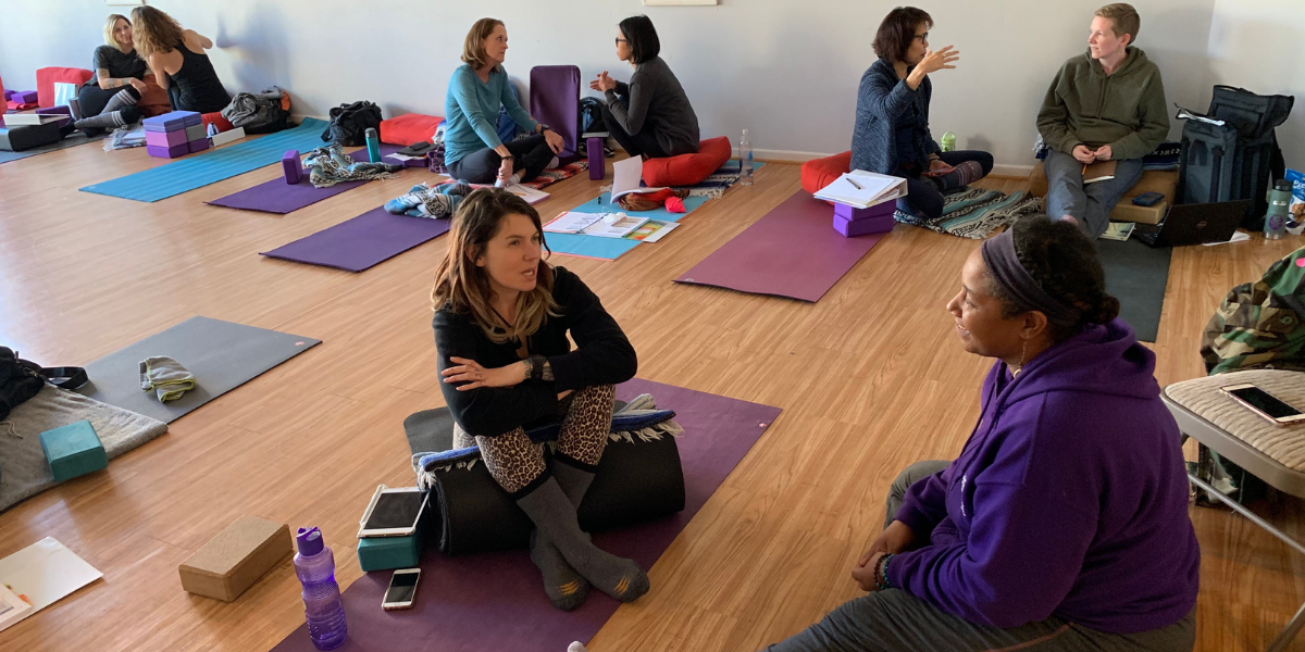 People discussing yoga training in a group setting