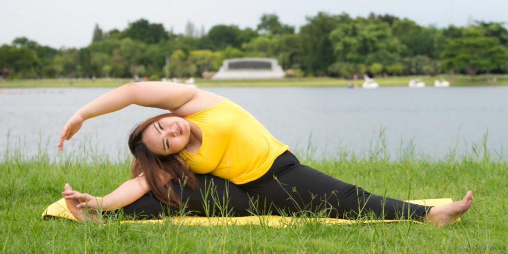 Fat woman exercising yoga in tree pose Stock Photo